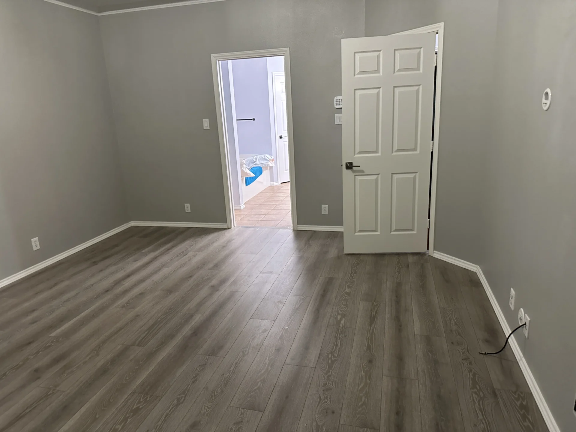 Empty room with wooden flooring and door.
