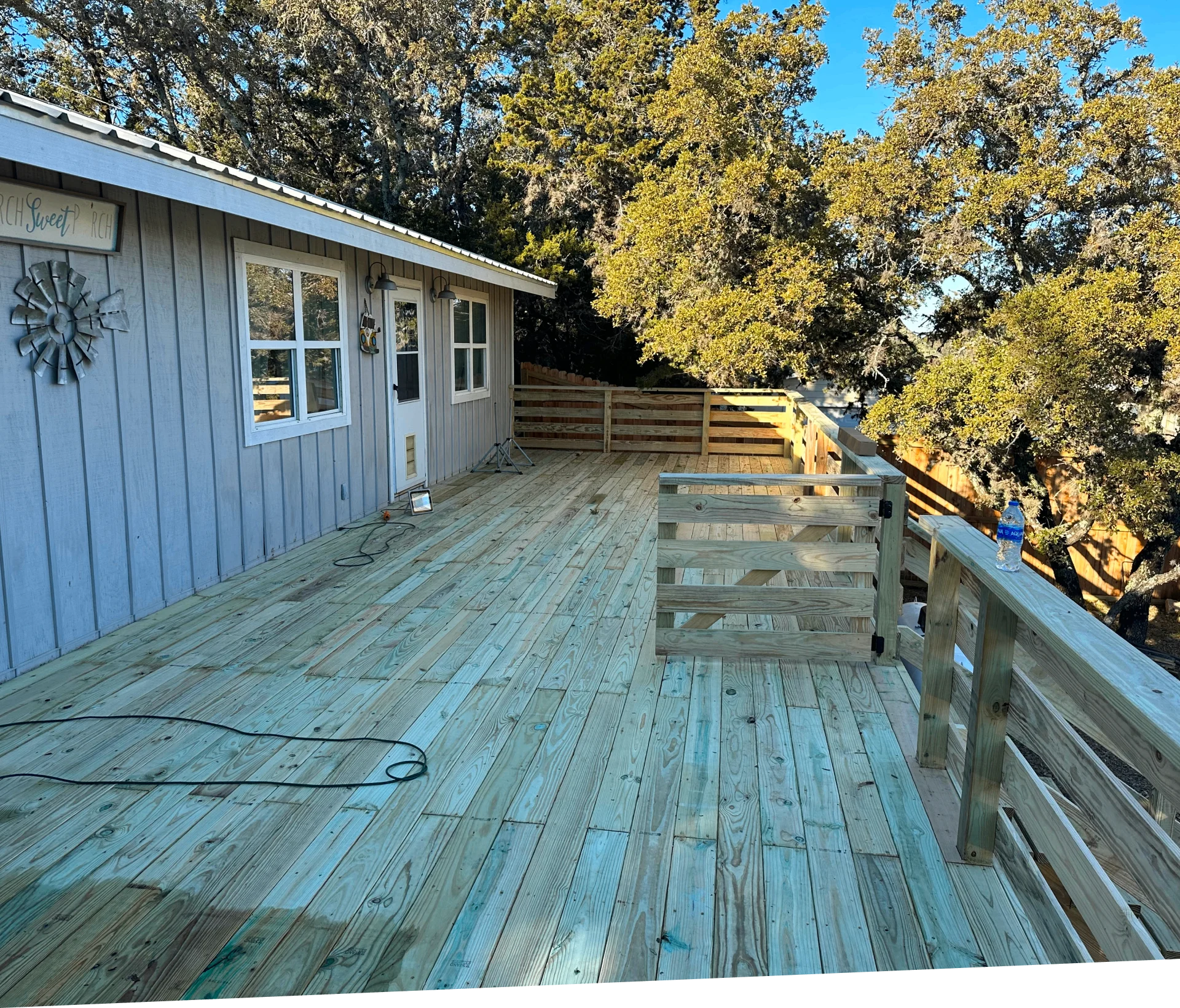 Wooden deck attached to a gray house.